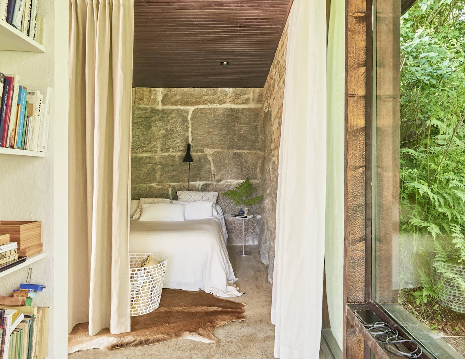 Dormitorio con paredes de piedra y techo de madera.